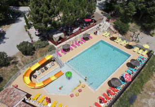Vista aerea della piscina, scivolo d’acqua e lettini colorati al Flower Camping La Rivière in Provenza, Francia.
