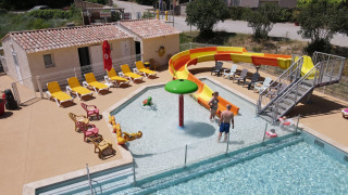 Piscina exterior con tobogán, tumbonas y huéspedes en Flower Camping La Rivière, Provenza, Francia.