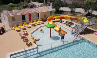 Piscina exterior con tobogán, tumbonas y huéspedes en Flower Camping La Rivière, Provenza, Francia.