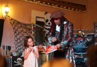 Un magicien déguisé en pirate amuse une fillette au Flower Camping La Rivière en Provence-Alpes-Côte d’Azur.