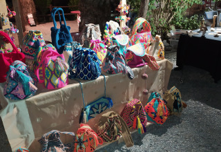 Colorful handmade bags displayed on a market stall at Flower Camping La Rivière, Provence, France.