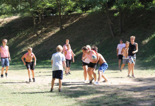 Børn og teenagere leger boldspil udendørs i solskin på Flower Camping La Rivière i Sydfrankrig.