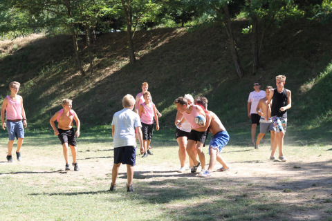 Kinderen en tieners spelen een balspel in de zon op Flower Camping La Rivière in Zuid-Frankrijk.