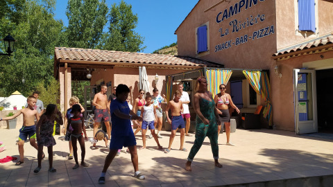 Kinderen en volwassenen nemen deel aan een dansactiviteit bij Flower Camping La Rivière in Zuid-Frankrijk.
