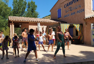 Gruppe børn og voksne deltager i udendørs danseaktivitet ved Flower Camping La Rivière i Provence, Frankrig.