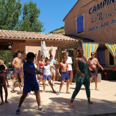 Niños y adultos participan en una actividad de baile al aire libre en Flower Camping La Rivière en Provenza, Francia.