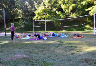 Udendørs yogaklasse under træer i Flower Camping La Rivière, Provence-Alpes-Côte d’Azur, Frankrig.