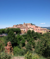 Vista panorámica de edificios de colores pastel en Saint-Maime, Provence-Alpes-Côte d’Azur, rodeados de vegetación.