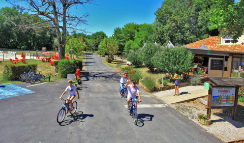 Feriepark Camping Le Périgord i Nouvelle-Aquitaine, Frankrig, med cyklende familier, grønne træer og udendørs aktiviteter.