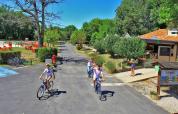 Feriepark Camping Le Périgord i Nouvelle-Aquitaine, Frankrig, med cyklende familier, grønne træer og udendørs aktiviteter.