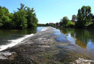 Vista del río en Camping Le Périgord en Nouvelle-Aquitaine, Francia, con agua clara y vegetación abundante.
