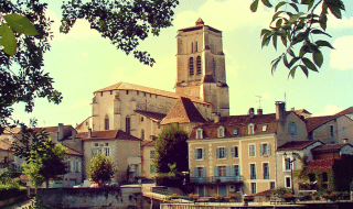 Veduta di Saint-Astier in Nouvelle-Aquitaine, Francia, con fiume, case storiche e campanile di chiesa.