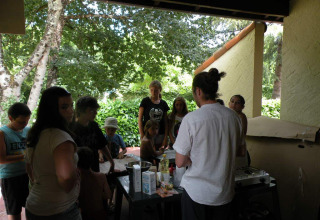 Gruppe mennesker samles under et overdækket område ved Camping Le Périgord feriepark i Frankrig.