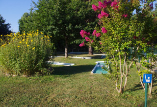 Grøn campingplads med blomster og minigolfbane på Camping Le Périgord i Nouvelle-Aquitaine, Frankrig.