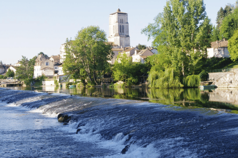 Vista del fiume e del paese di Saint-Astier in Nouvelle-Aquitaine, Francia, con alberi e case verdi intorno.