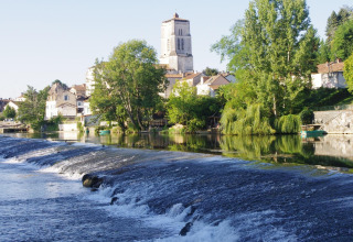 Udsigt over floden og byen Saint-Astier i Nouvelle-Aquitaine, Frankrig, omgivet af grønne træer og huse.