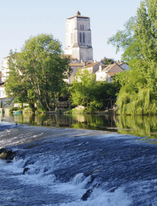 Vista del fiume e del paese di Saint-Astier in Nouvelle-Aquitaine, Francia, con alberi e case verdi intorno.