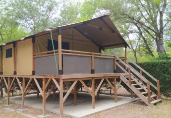 Elevated Lodge op palen Confort with wooden and canvas structure set amidst lush green forest trees.