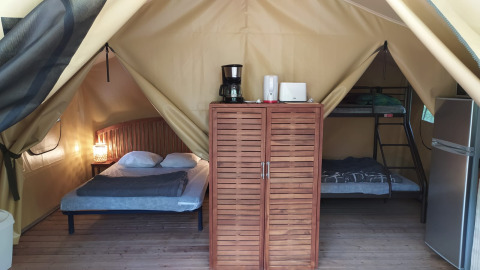 Interieur van Lodge op palen Confort op Flower Camping La Rivière in Frankrijk met bed en stapelbed.
