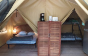 Vista interna della Lodge op palen Confort al Flower Camping La Rivière in Francia con letto e letto a castello.