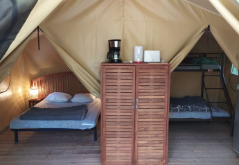 Interieur van Lodge op palen Confort op Flower Camping La Rivière in Frankrijk met bed en stapelbed.
