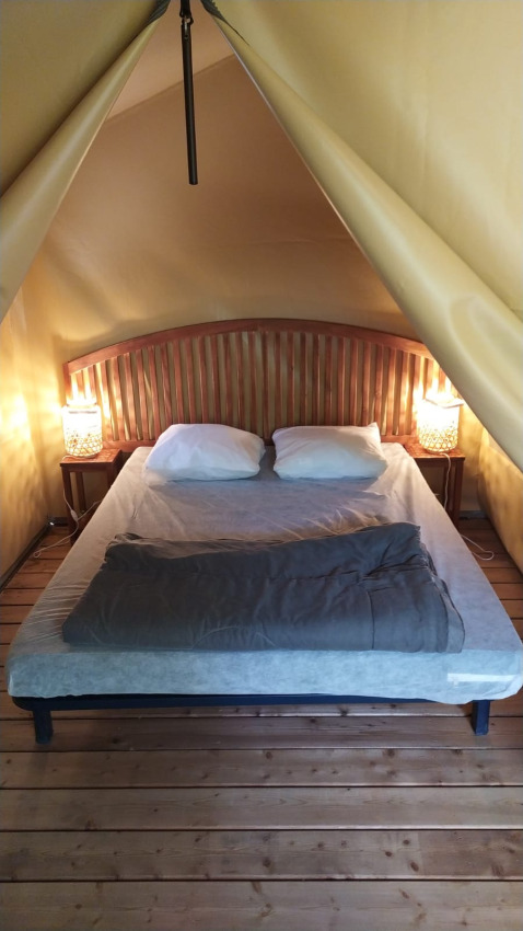 Gemütliches Schlafzimmer mit Doppelbett, Holzboden und Nachttischen in der Lodge op palen Confort in Frankreich.