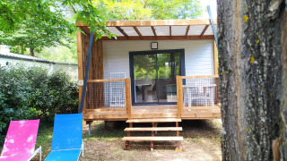 Chalet Cajou Confort al Flower Camping La Rivière in Francia, circondato da alberi e natura.