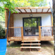 Chalet Cajou Confort al Flower Camping La Rivière in Francia, circondato da alberi e natura.