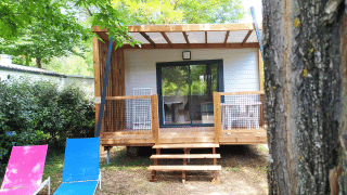 Chalet Cajou Confort al Flower Camping La Rivière in Francia, circondato da alberi e natura.