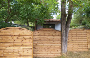 Wooden fence in front of a chalet at Chalet Cajou Confort, Flower Camping La Rivière, surrounded by trees.