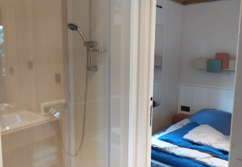 Et kig ind i et værelse på Chalet Cajou Confort med seng, bruser og moderne interiør ved Flower Camping La Rivière.