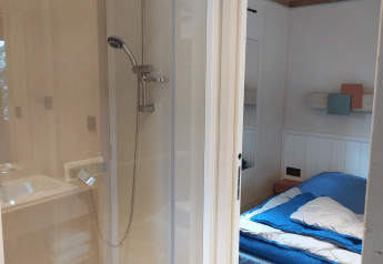 Habitación con cama y ducha en el Chalet Cajou Confort de Flower Camping La Rivière en Francia.