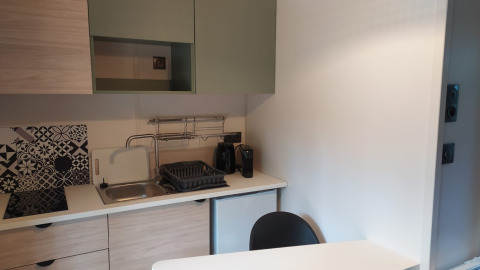 Moderne lille tekøkken på Chalet Cajou Confort med vask, komfur, sort stol og hvide skabe.