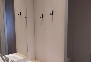 Moderne badkamer in Chalet Cajou Confort met wastafel, spiegel, handdoeken en toilet bij Flower Camping La Rivière.