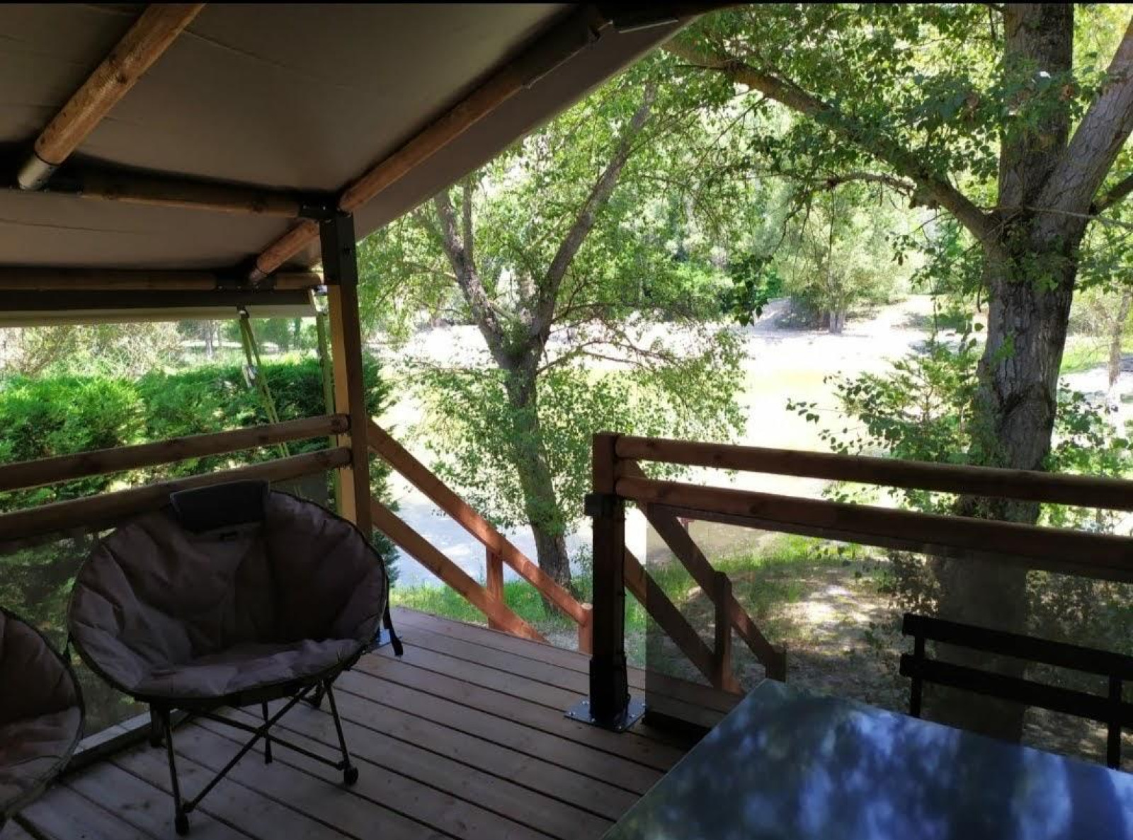 Uitzicht vanaf Lodge op palen Confort 46m² safaritent bij Flower Camping La Rivière, terras en groene omgeving.