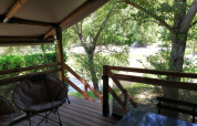 View from the Lodge op palen Confort 46m² safari tent at Flower Camping La Rivière, terrace and green scenery.