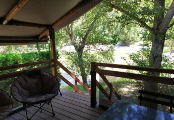 Zicht vanop het terras van Lodge op palen Confort 46m² safaritent bij Flower Camping La Rivière, groene natuur.
