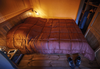 Cozy bedroom with warm bed and wooden decor in Lodge op palen Confort 46m² at Flower Camping La Rivière, France.