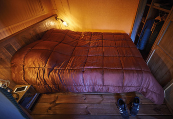 Dormitorio acogedor con cama abrigada y decoración de madera en Lodge op palen Confort 46m², Flower Camping La Rivière.