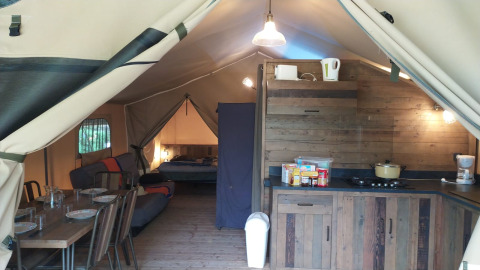 Vue intérieure de la Lodge on stilts Confort au Flower Camping La Rivière, cuisine et table à manger incluses.