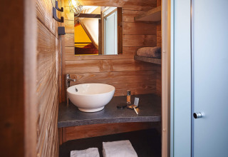 Badkamer met houten afwerking, waskom en douche in Lodge on stilts Confort, Flower Camping La Rivière, Frankrijk.