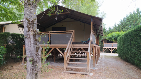 Voorzijde van Lodge on stilts Confort bij Flower Camping La Rivière in Frankrijk, met terras en groen.