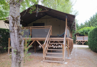 Voorzijde van Lodge on stilts Confort bij Flower Camping La Rivière in Frankrijk, met terras en groen.