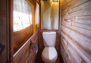 Bagno rivestito in legno con WC, finestra e tenda, Lodge on stilts Confort, Flower Camping La Rivière, Francia.
