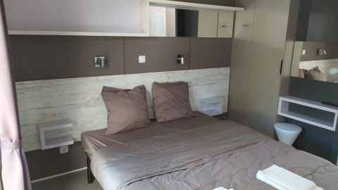 Habitación de glamping moderna con cama doble, decoración elegante y tonos neutros y acogedores.