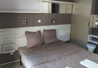 Camera glamping moderna con letto matrimoniale, arredi eleganti e tonalità naturali e rilassanti.