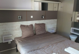 Habitación de glamping moderna con cama doble, decoración elegante y tonos neutros y acogedores.