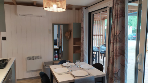 Interior of a glamping accommodation featuring a set dining table, sliding doors, and a view of the terrace.