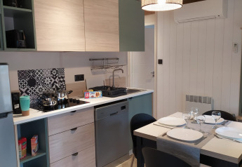 Alloggio glamping moderno con cucina attrezzata, tavolo da pranzo, lavastoviglie e arredo elegante.
