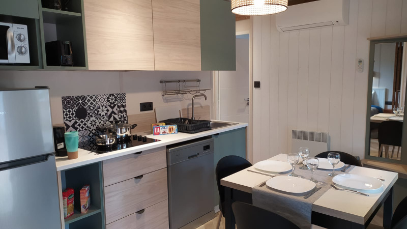 Hébergement glamping moderne avec cuisine équipée, table à manger, lave-vaisselle et décoration soignée.